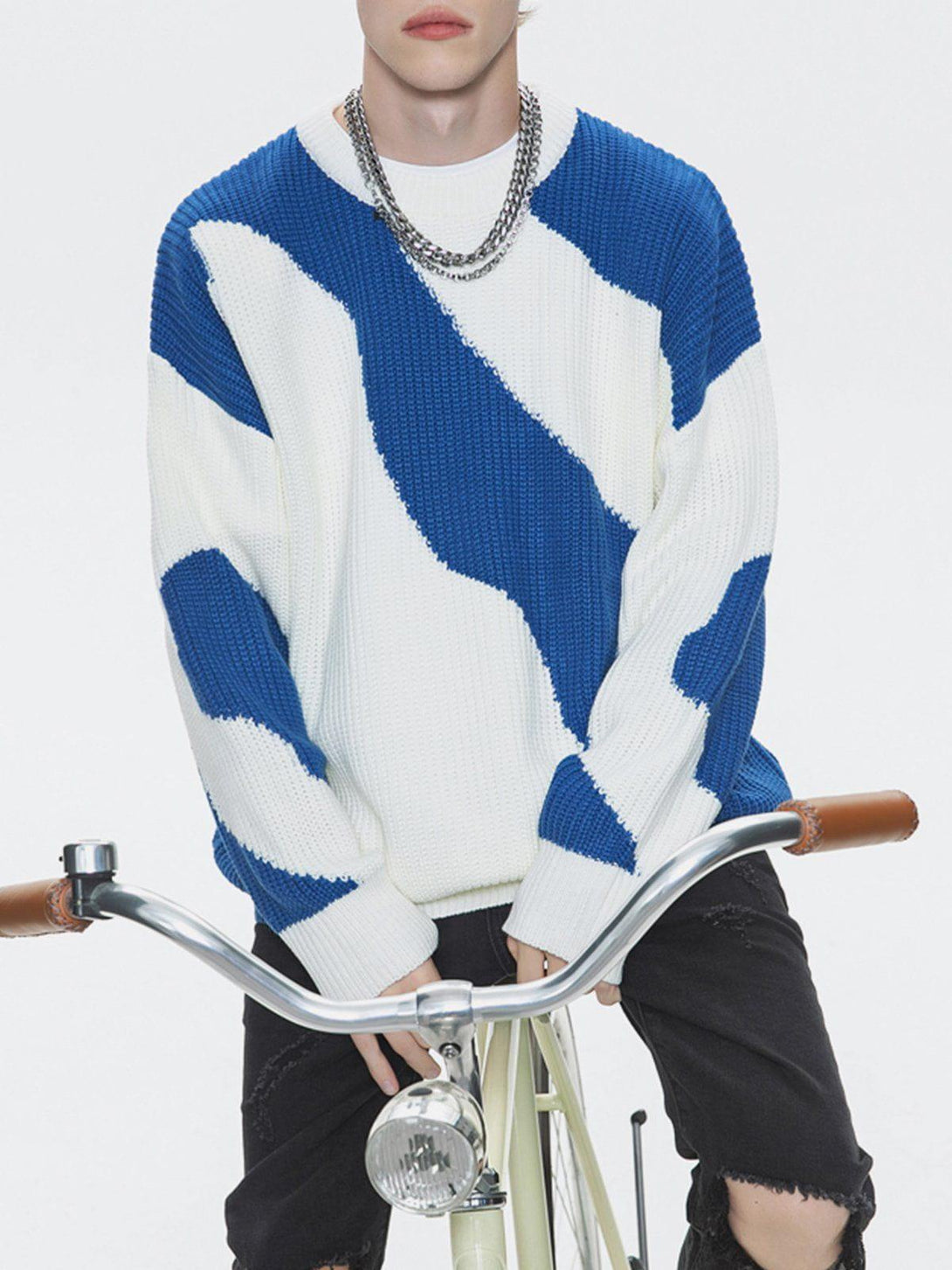 Model wearing blue and white contrast sweater by TALISHKO, paired with chain necklace.