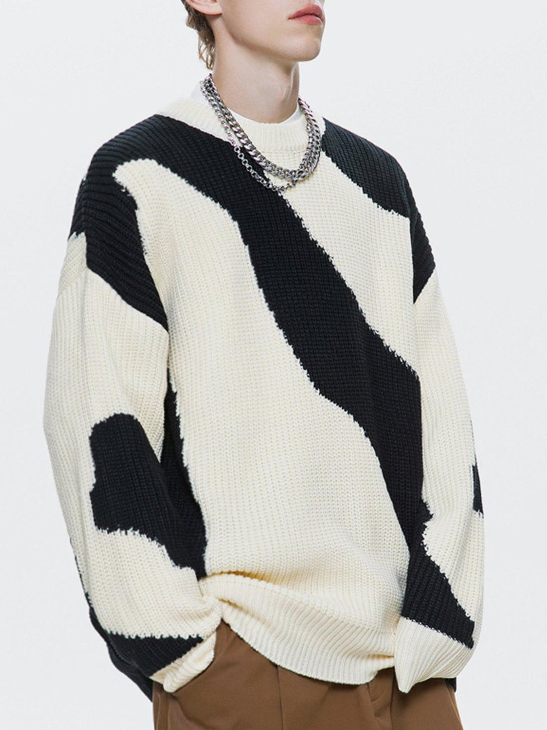 Model wearing a black and white abstract sweater by TALISHKO, styled with a chunky chain necklace.