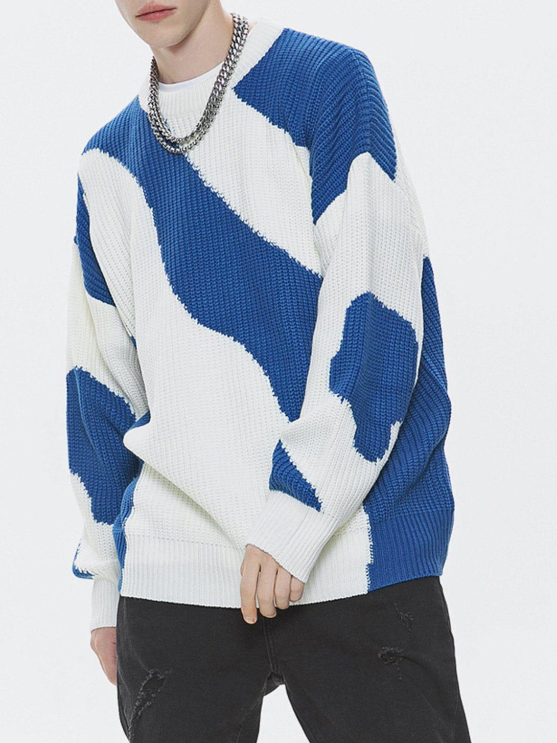 Model wearing a blue and white pattern sweater by TALISHKO, styled with a chain necklace.