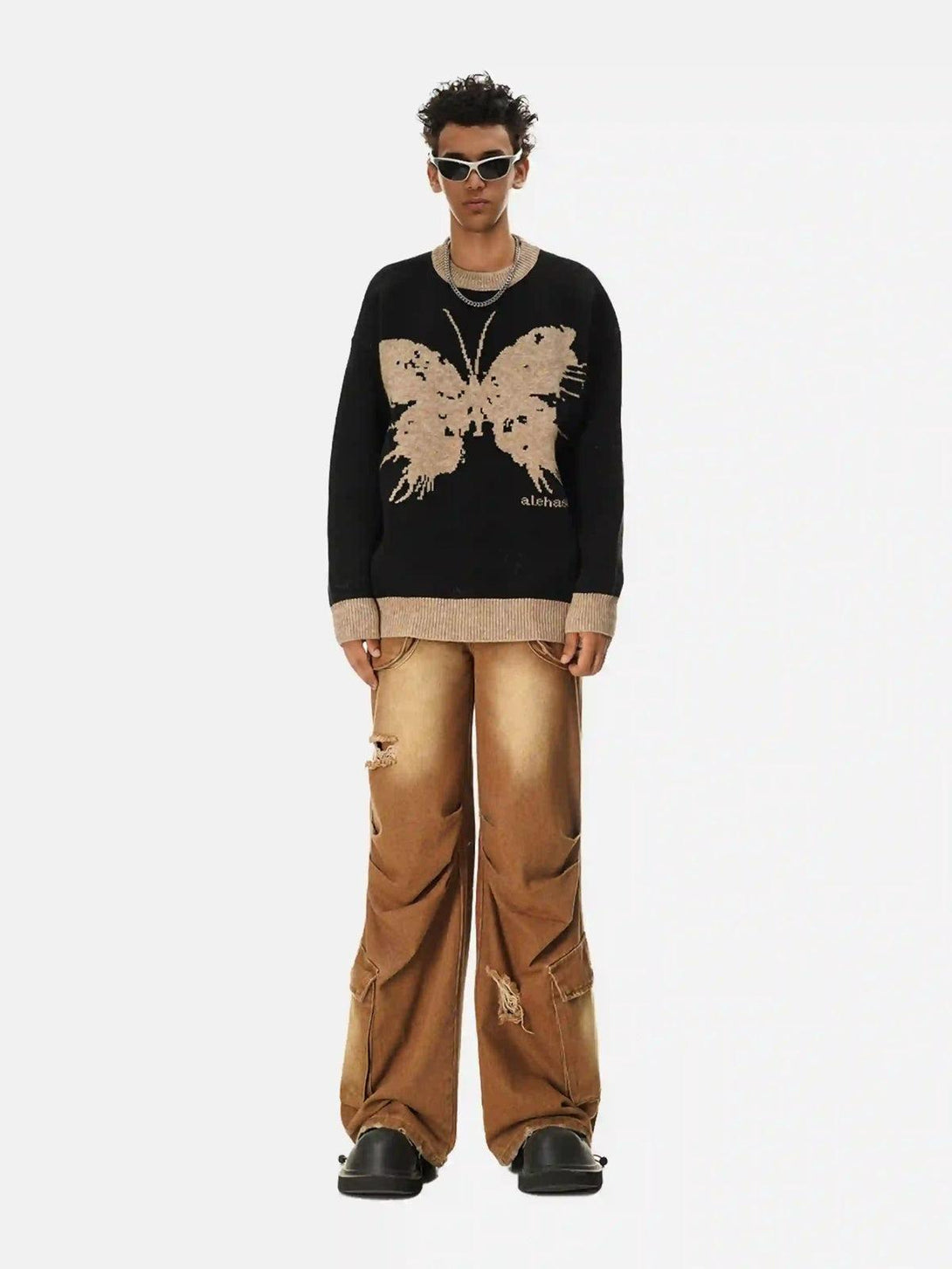 Model wears TALISHKO jacquard butterfly sweater with distressed brown pants and chunky shoes.
