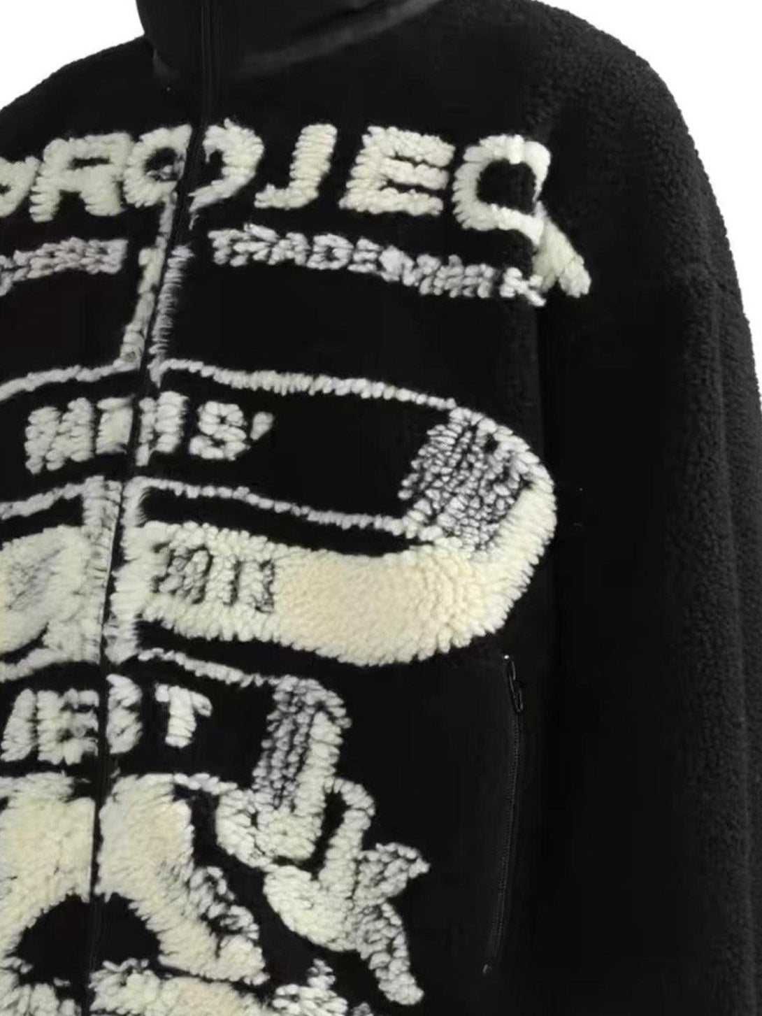 A close-up of a black sherpa jacket by TALISHKO, showcasing intricate jacquard patterns.