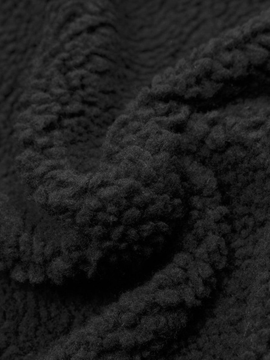 Zoomed-in texture of the black sherpa fabric by TALISHKO, highlighting its cozy jacquard detail.