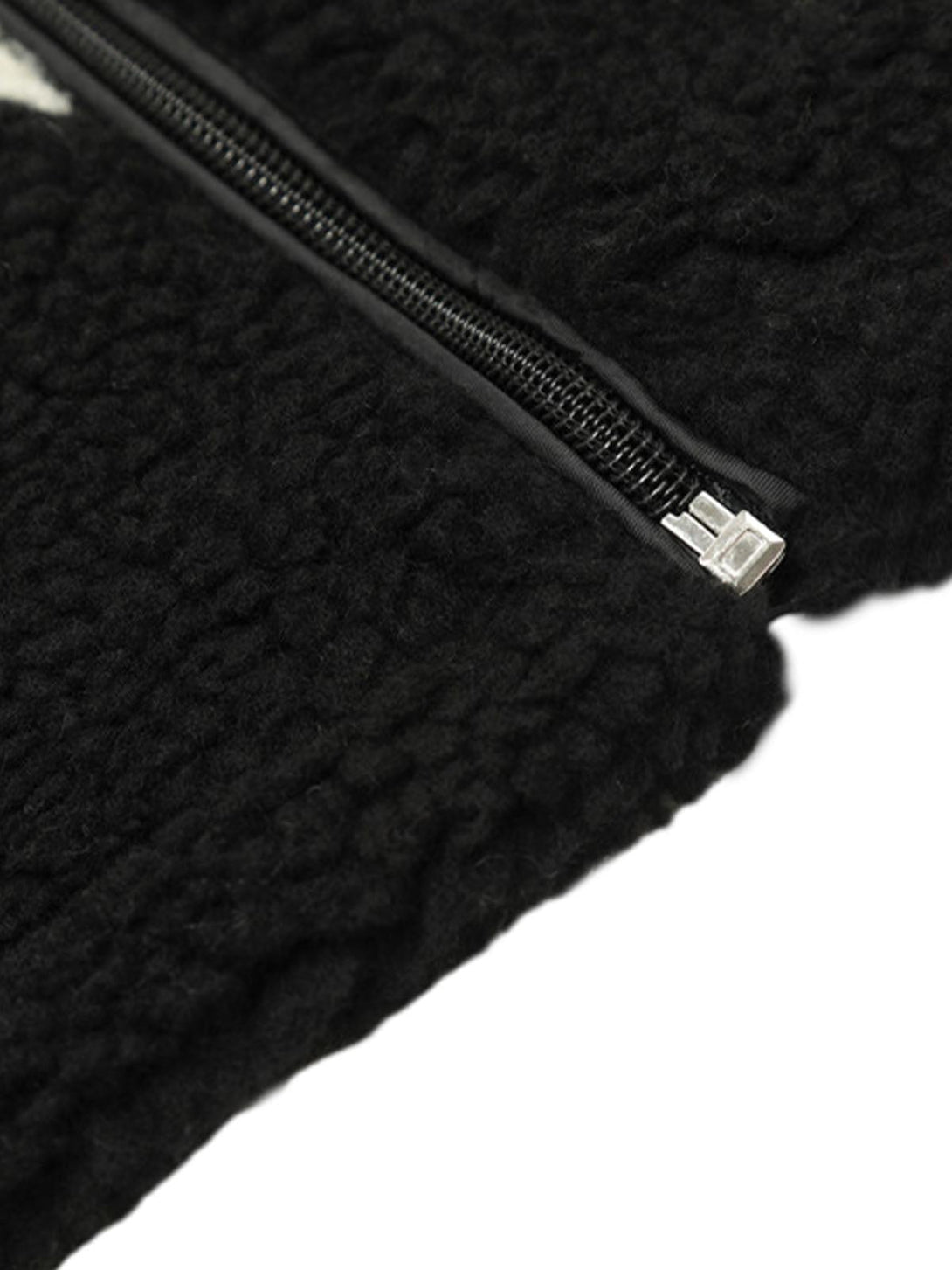 Focusing on the sleek zipper and textured fabric of the black sherpa jacket by TALISHKO.