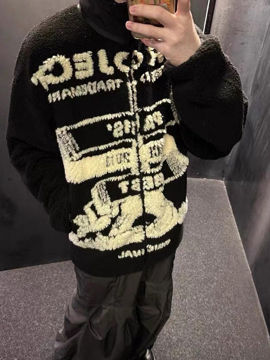 Model wearing a TALISHKO black sherpa jacket with bold jacquard graphics and stand collar.