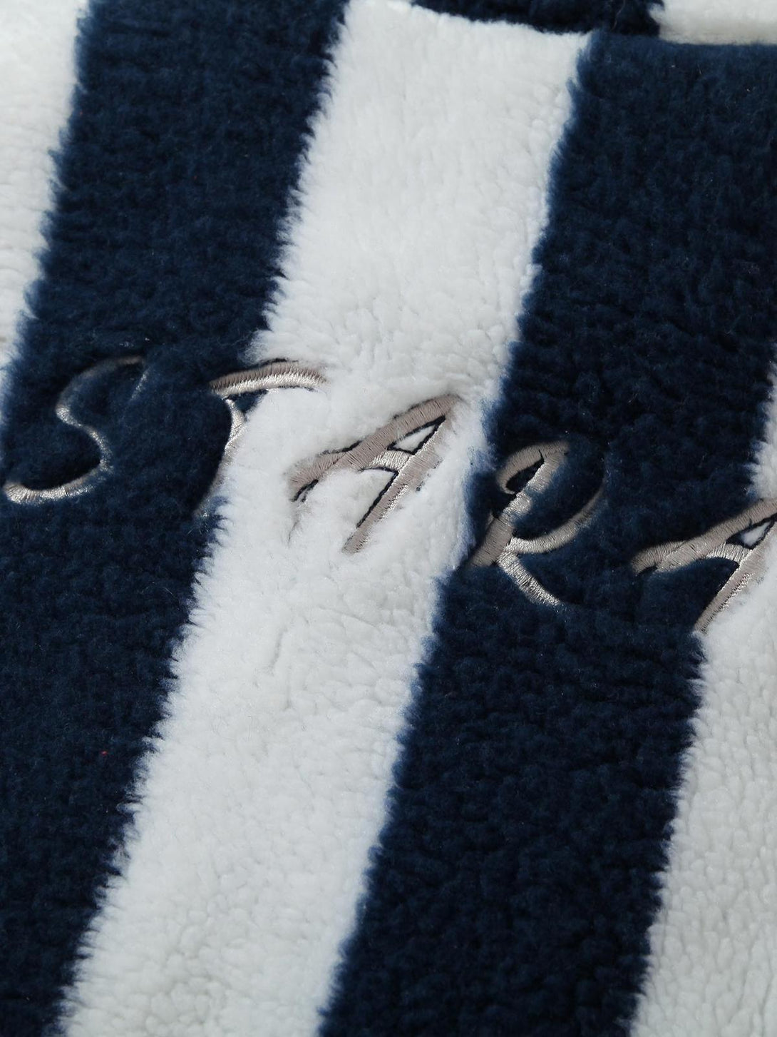 Detailed look at TALISHKO's striped sherpa fabric, emphasizing its plush texture and embroidery.