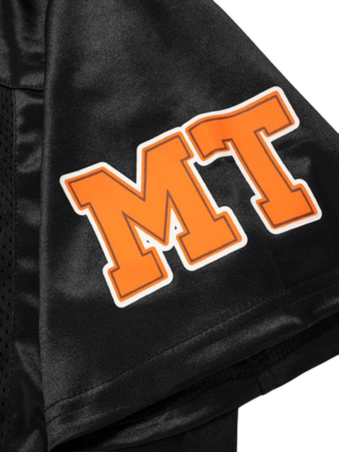 Close-up of TALISHKO's black jersey T-shirt sleeve with bold orange "MT" lettering.