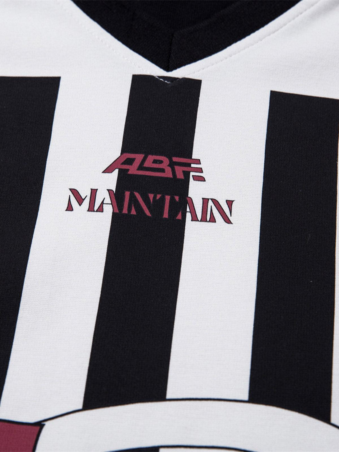 TALISHKO jersey polo shirt featuring black and white stripes with bold "Maintain" graphic detail.