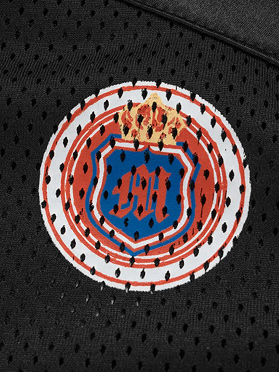 Focusing on the intricate emblem detail on TALISHKO's black jersey T-shirt, showcasing sporty flair.