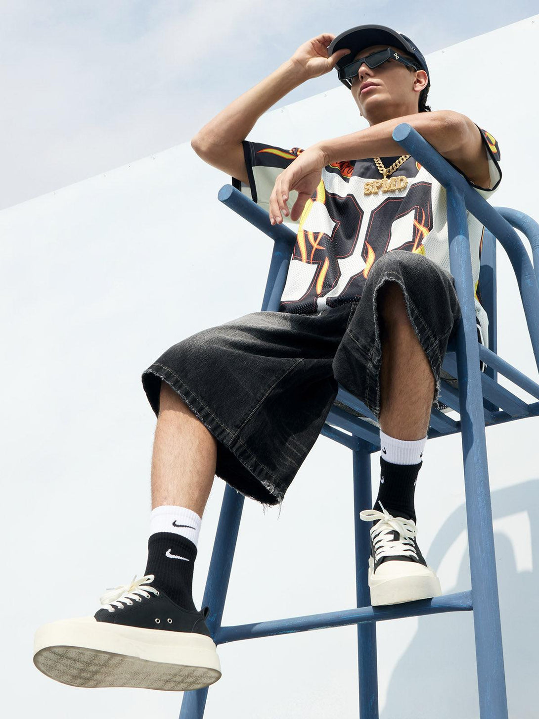 Model in a flame print jersey-style T-shirt by TALISHKO, exuding a cool, laid-back vibe.