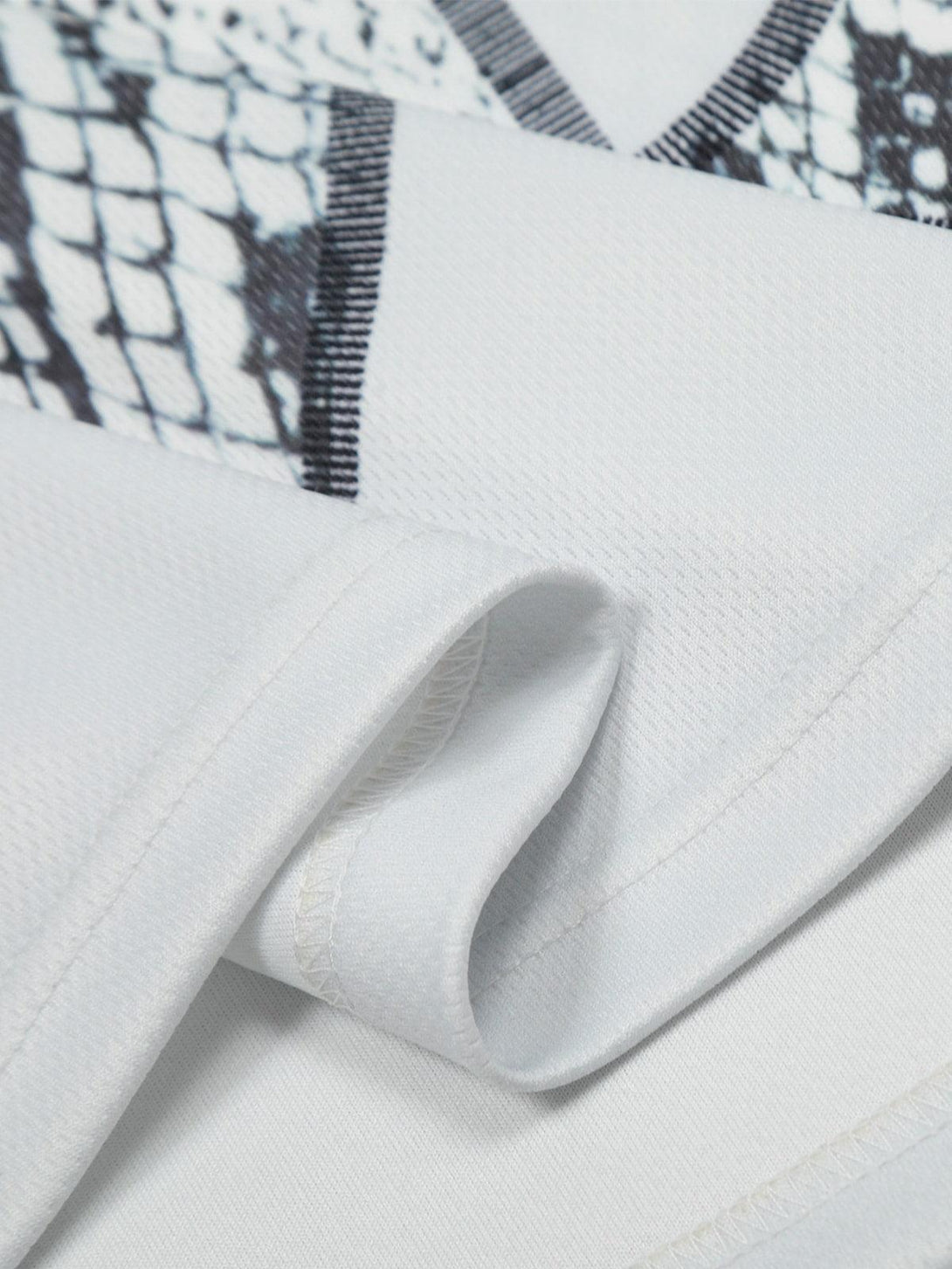 Detailed fabric and stitching of TALISHKO jersey-style T-shirt with snake print pattern.