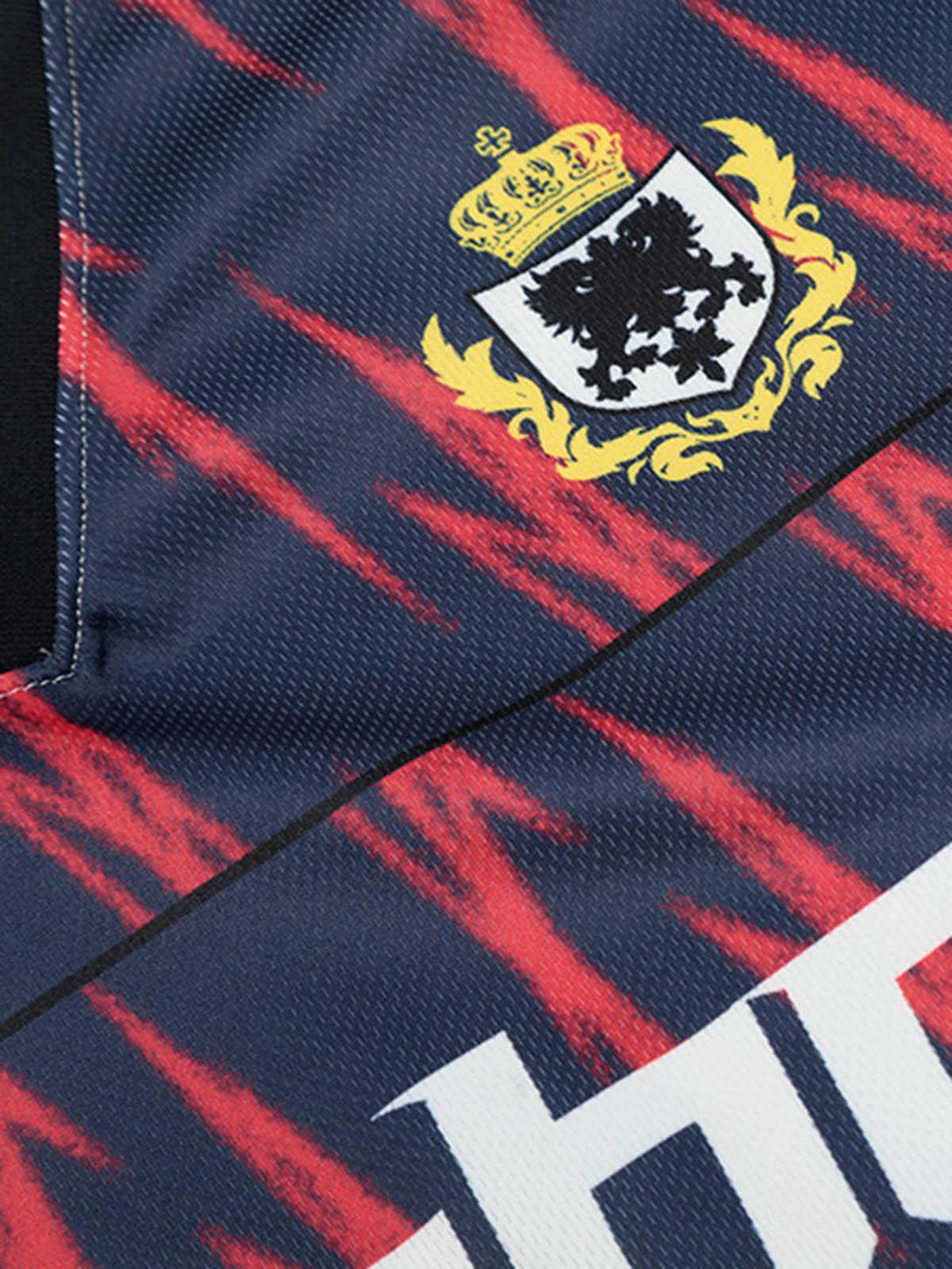 A tight crop highlighting the TALISHKO jersey's crest and bold red patterns on navy fabric.