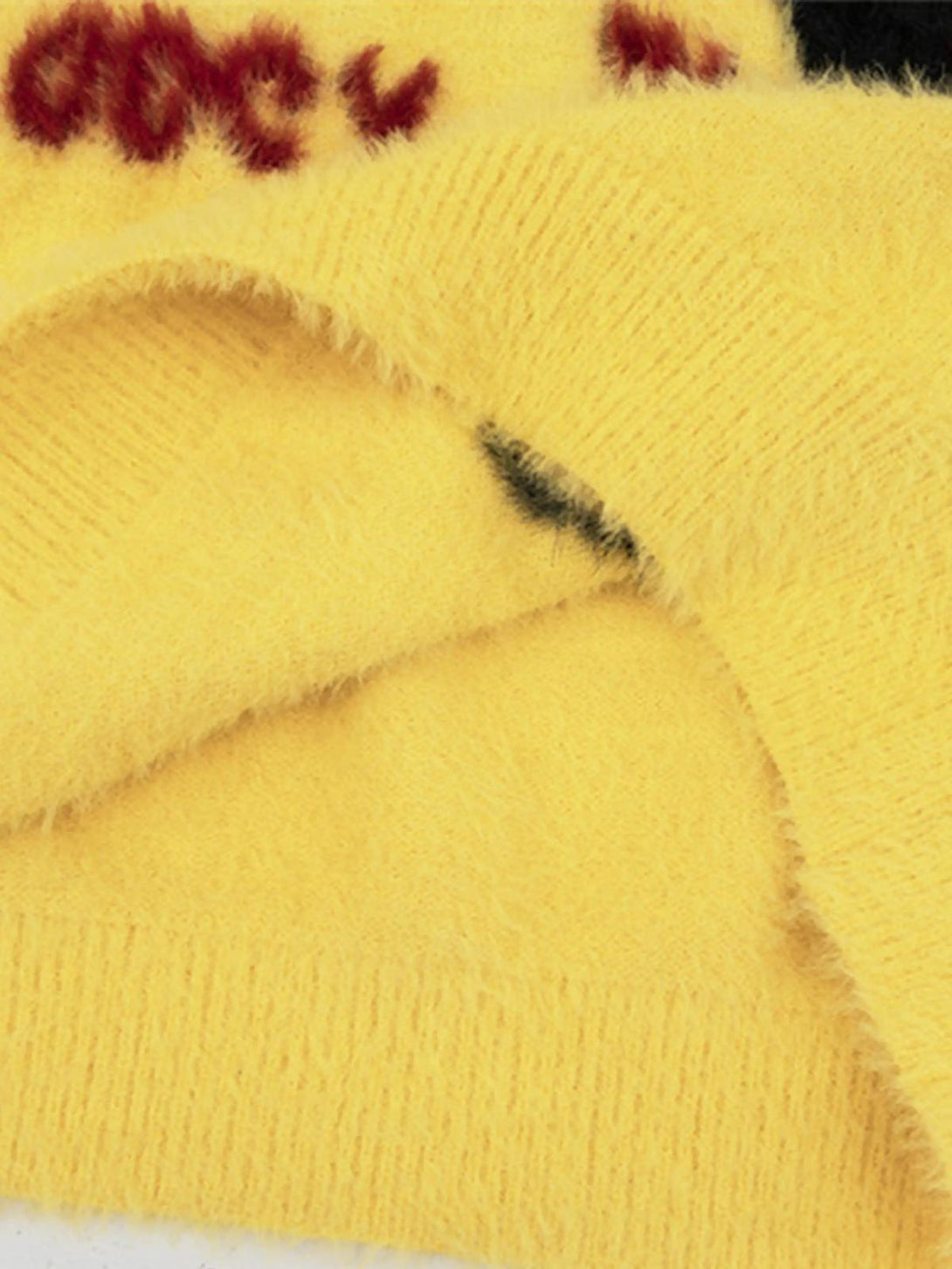 A close-up of the soft, fuzzy texture on a yellow kitten jacquard mohair sweater by TALISHKO.