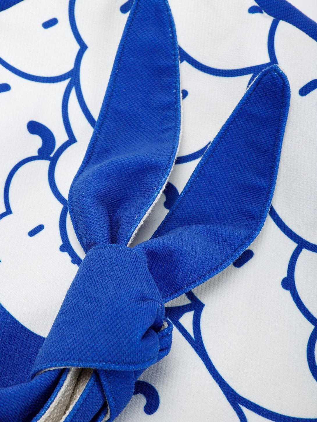 Playful knotted strap detail on the TALISHKO Klein blue canvas bag with cartoon pattern.