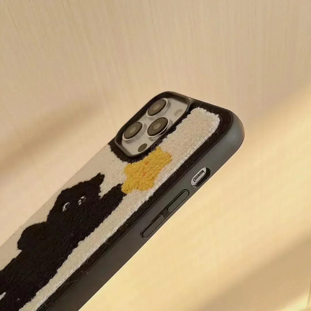 A close-up of a TALISHKO iPhone case showcasing a plush black bear with a yellow star design.