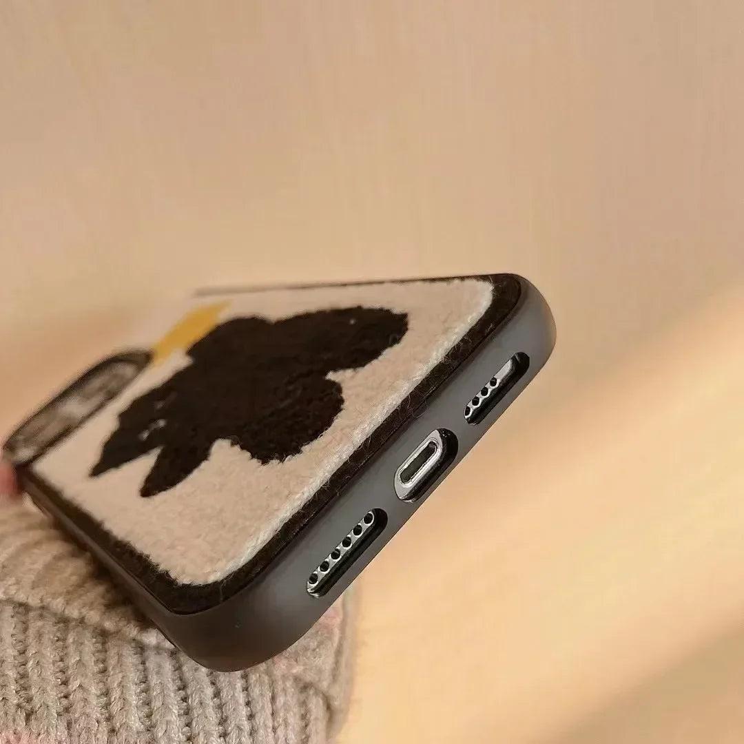 A detailed view of a TALISHKO plush iPhone case with a charming black bear design.