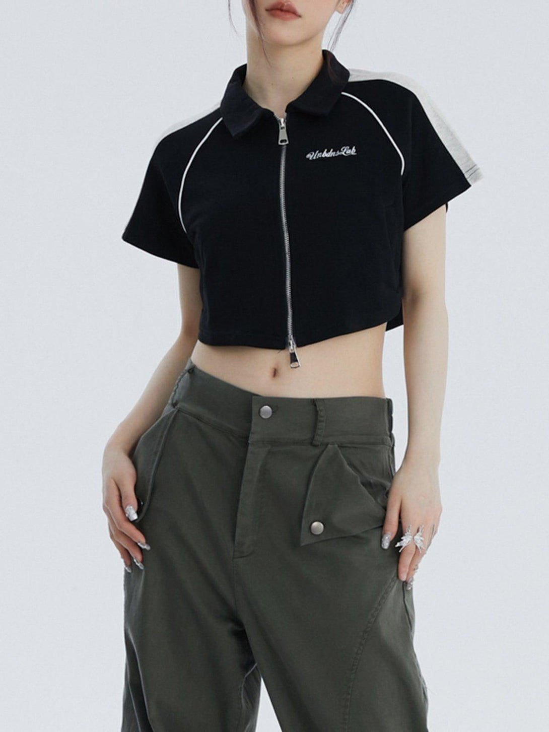 Model showcasing a TALISHKO cropped colorblock tee with lapel and zipper, styled with olive pants.
