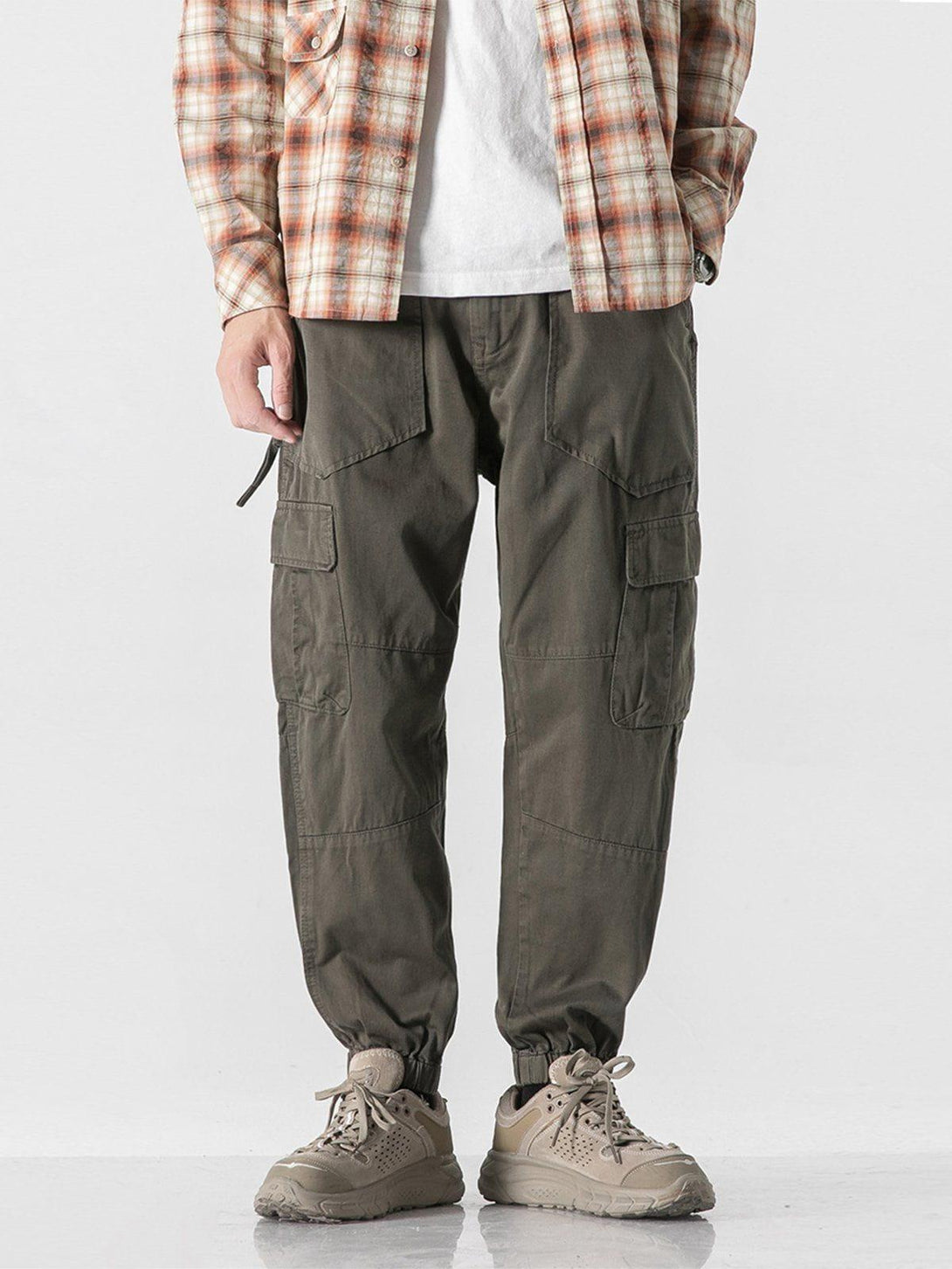 Model wearing TALISHKO cargo pants with multiple pockets, paired with plaid shirt and sneakers.
