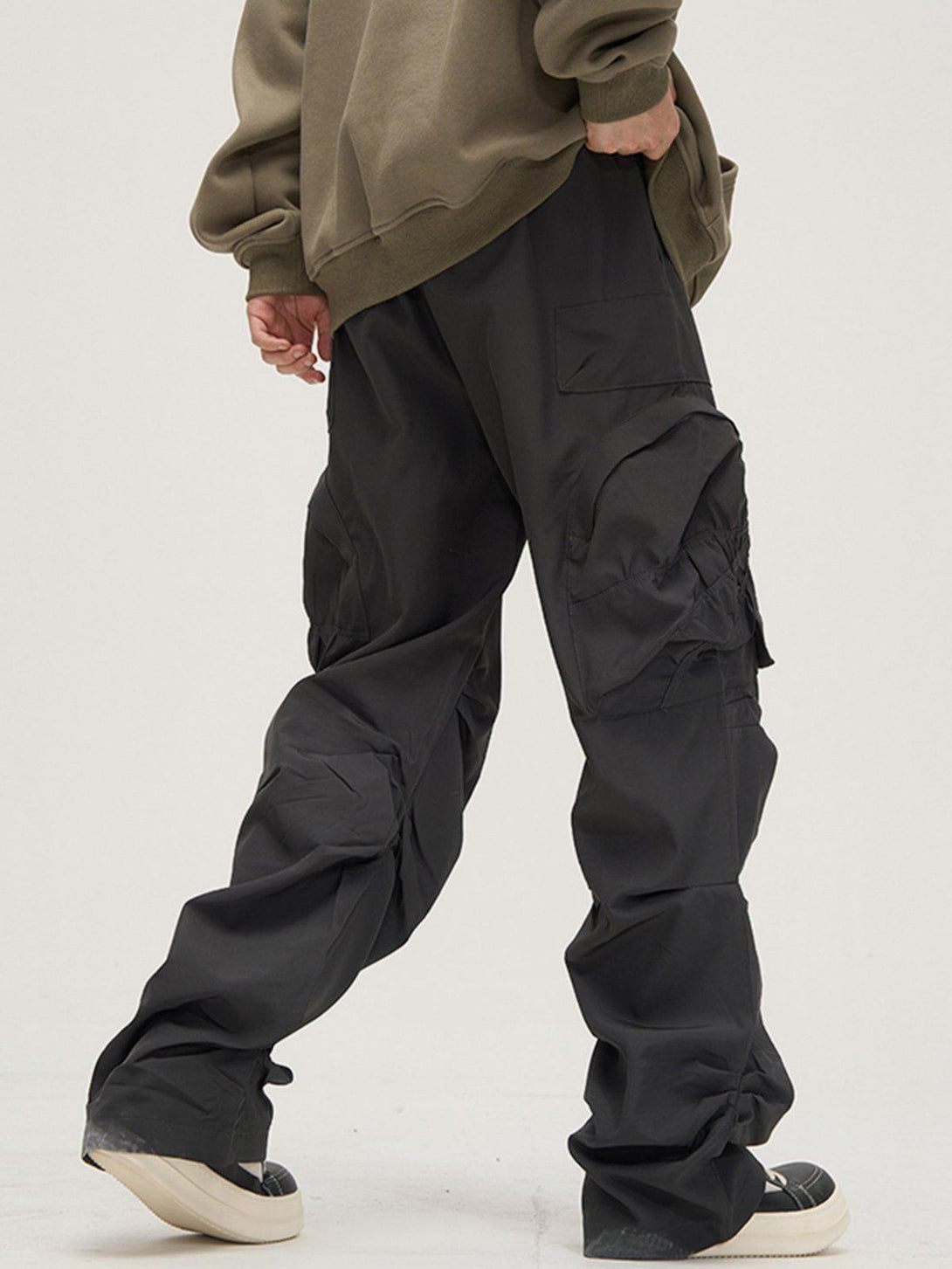 TALISHKO cargo pants with a wrinkled look and large pockets, shown from the back with sneakers.