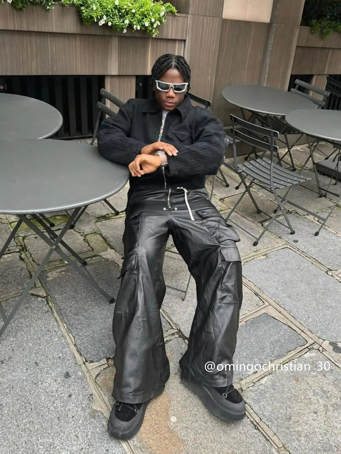 Model wearing TALISHKO black wide-leg flared pants, featuring layered pockets, exuding urban flair.