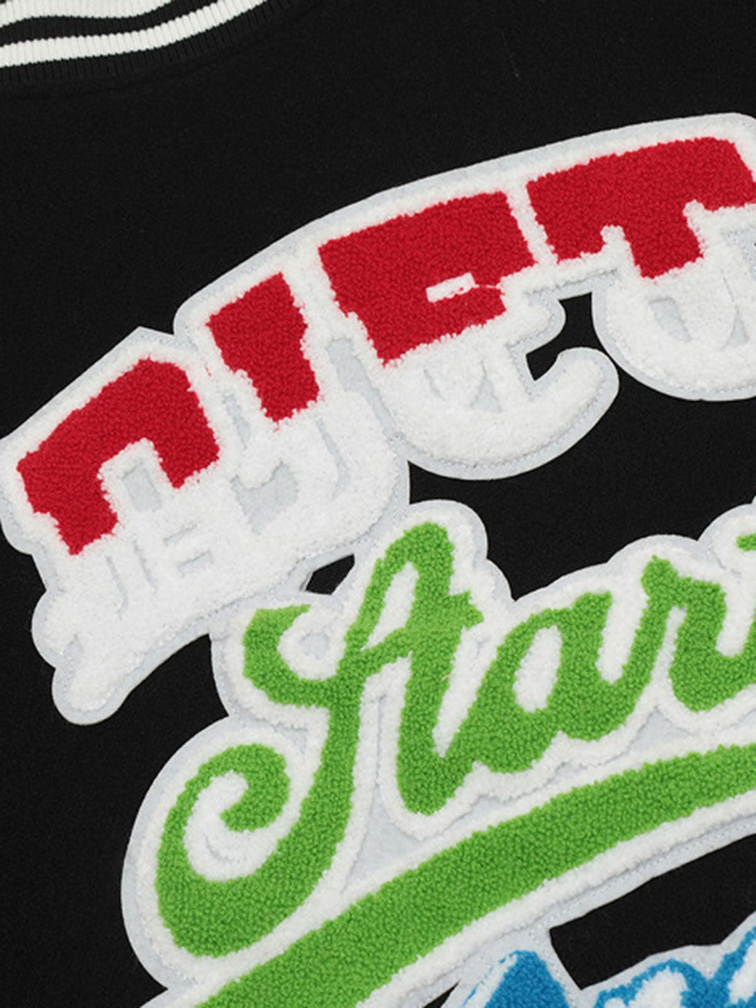 A detailed view of TALISHKO bomber jacket's colorful embroidered lettering on black fabric.