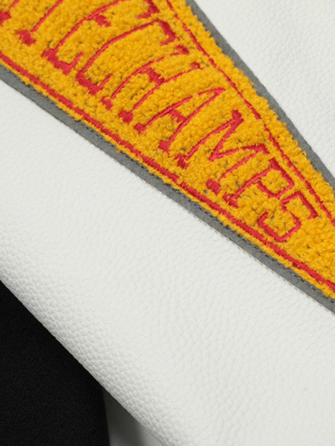 A tight crop highlighting TALISHKO's embroidered patchwork on the leather bomber jacket.