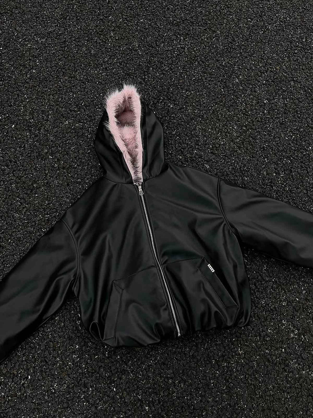 TALISHKO's black leather jacket with a pink fur-lined hood, highlighting its stylish front design.