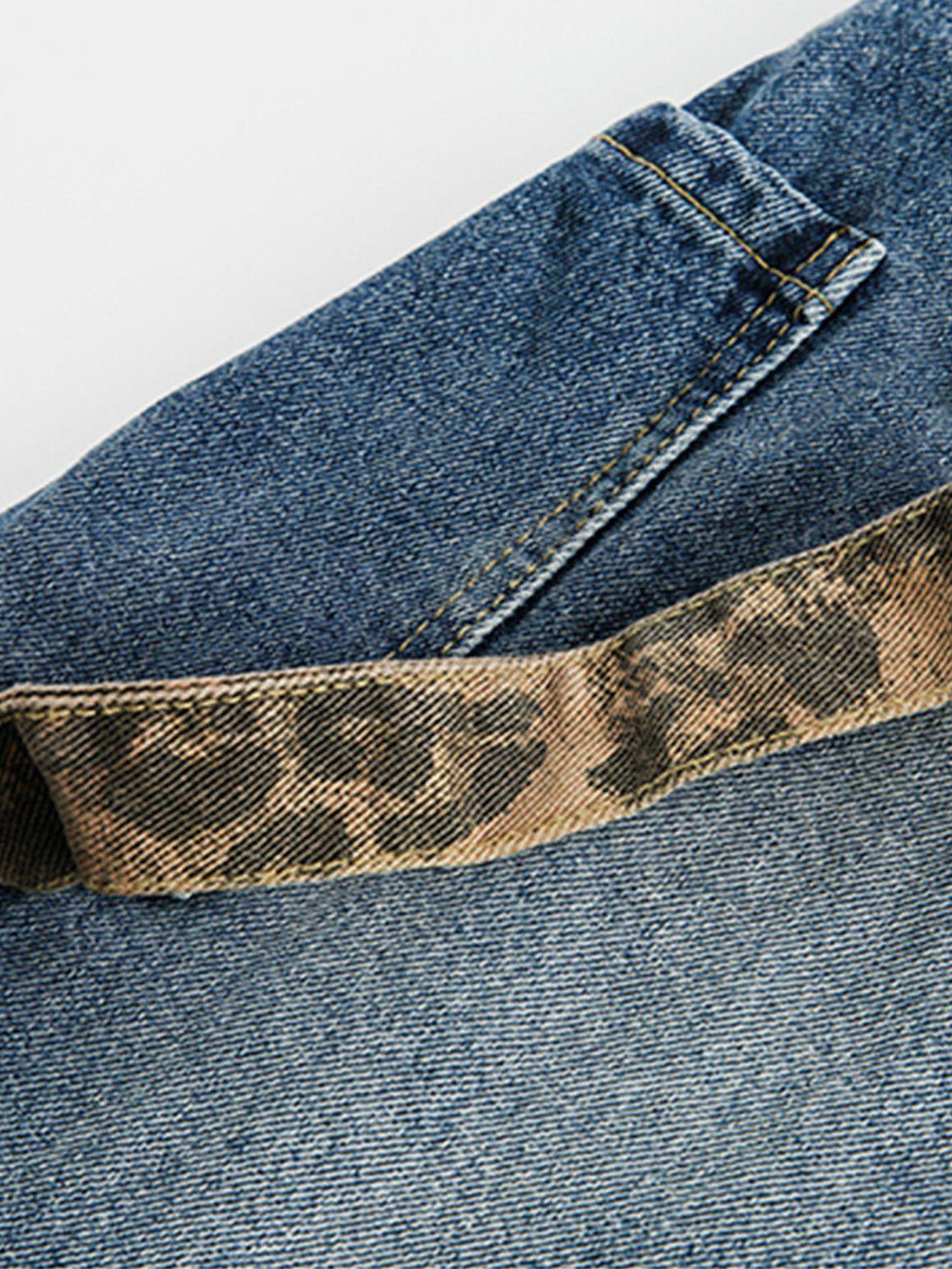 A detailed view of TALISHKO jeans highlighting leopard print cuffs and denim texture.
