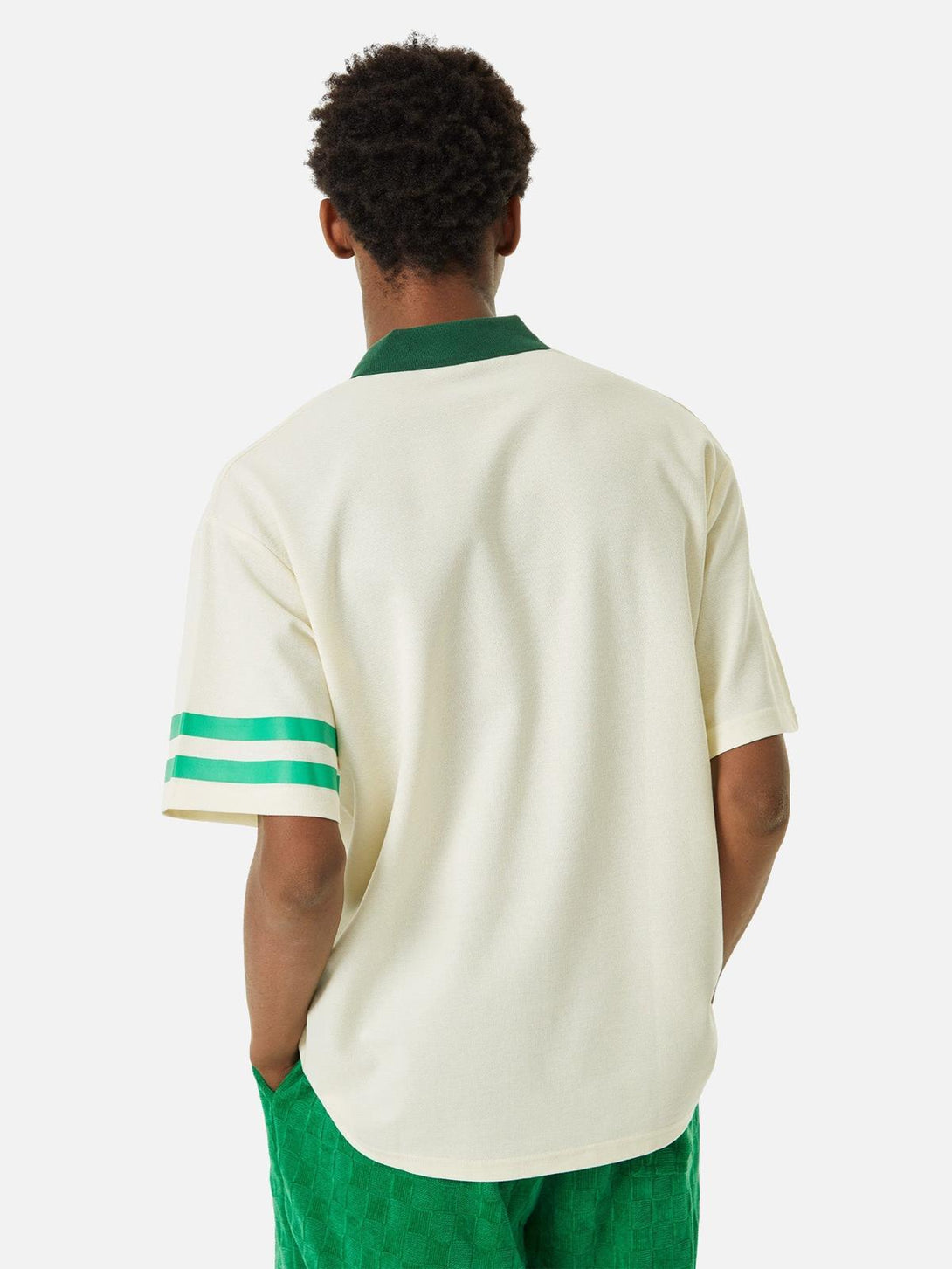 Back view of TALISHKO polo shirt featuring green collar and striped sleeves, paired with vibrant shorts.