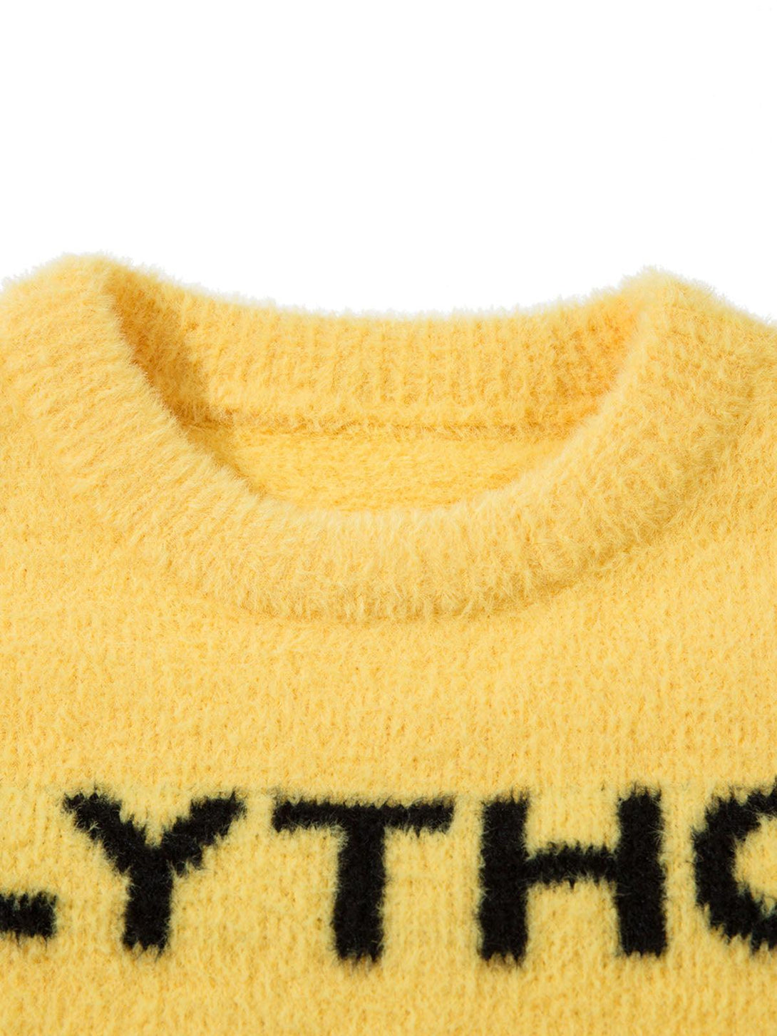 Zoomed-in texture of a yellow letter graphic sweater by TALISHKO, highlighting soft fabric.