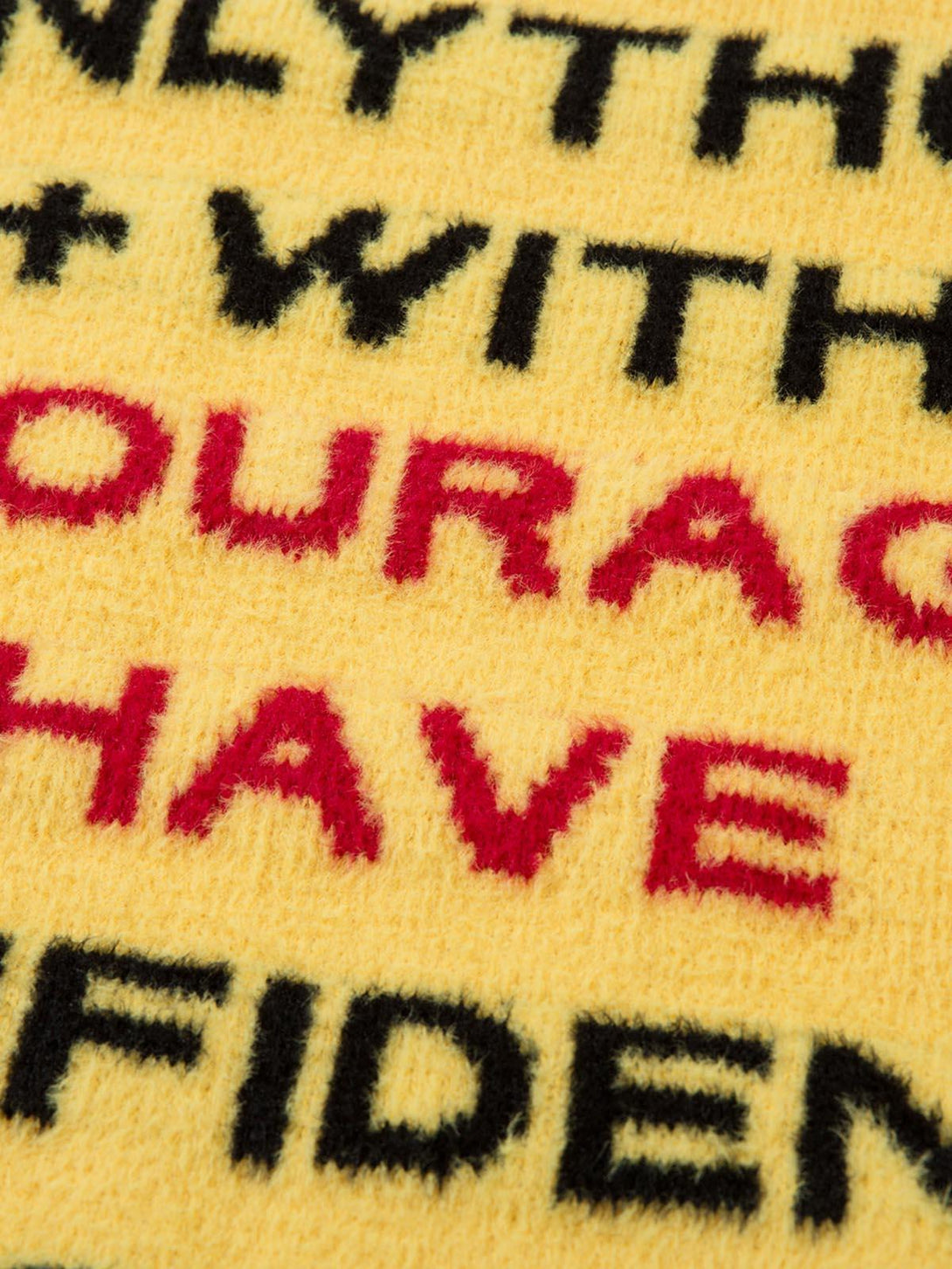 Intricate look at the bold lettering on a yellow sweater by TALISHKO, highlighting soft texture.