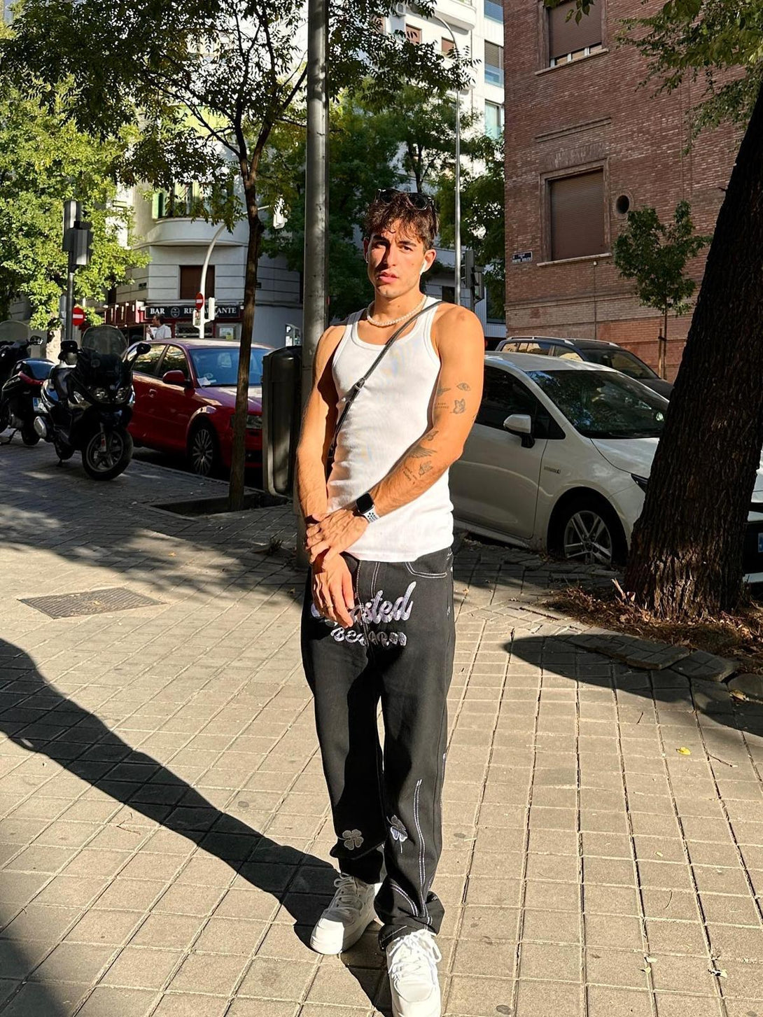 Model in urban setting wearing TALISHKO's baggy jeans with lucky clover embroidery.
