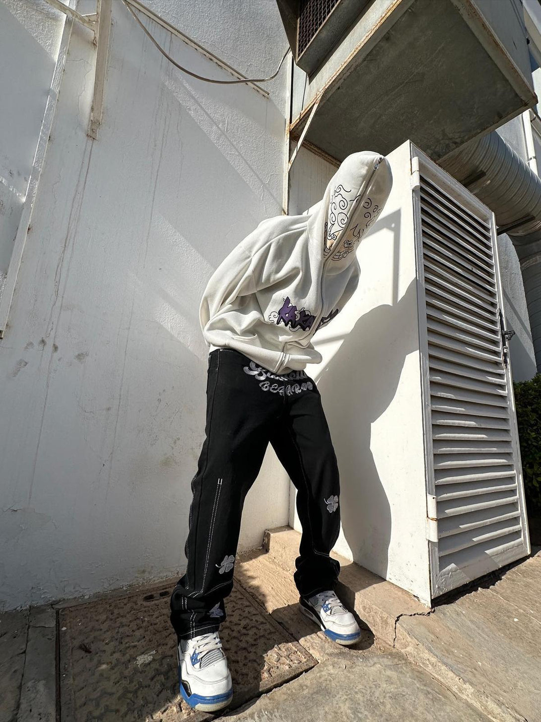 Model showcasing TALISHKO's baggy jeans with lucky clover embroidery in a streetwear style.