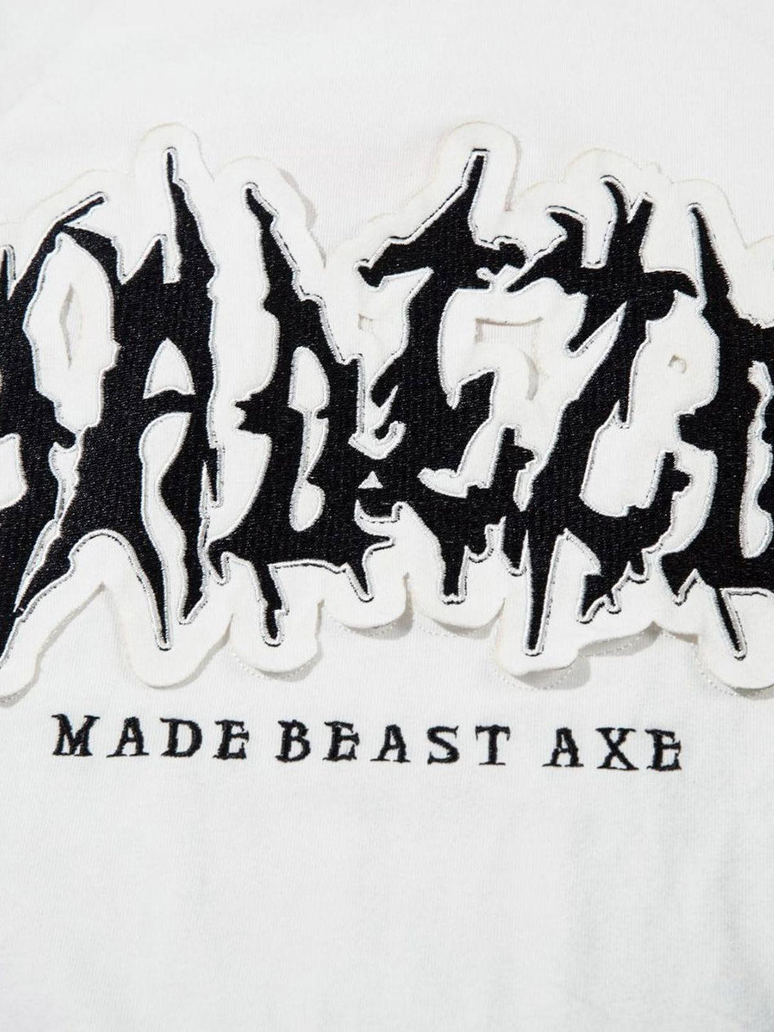 Detailed fabric and stitching of a TALISHKO tank top, featuring bold letter patchwork design.