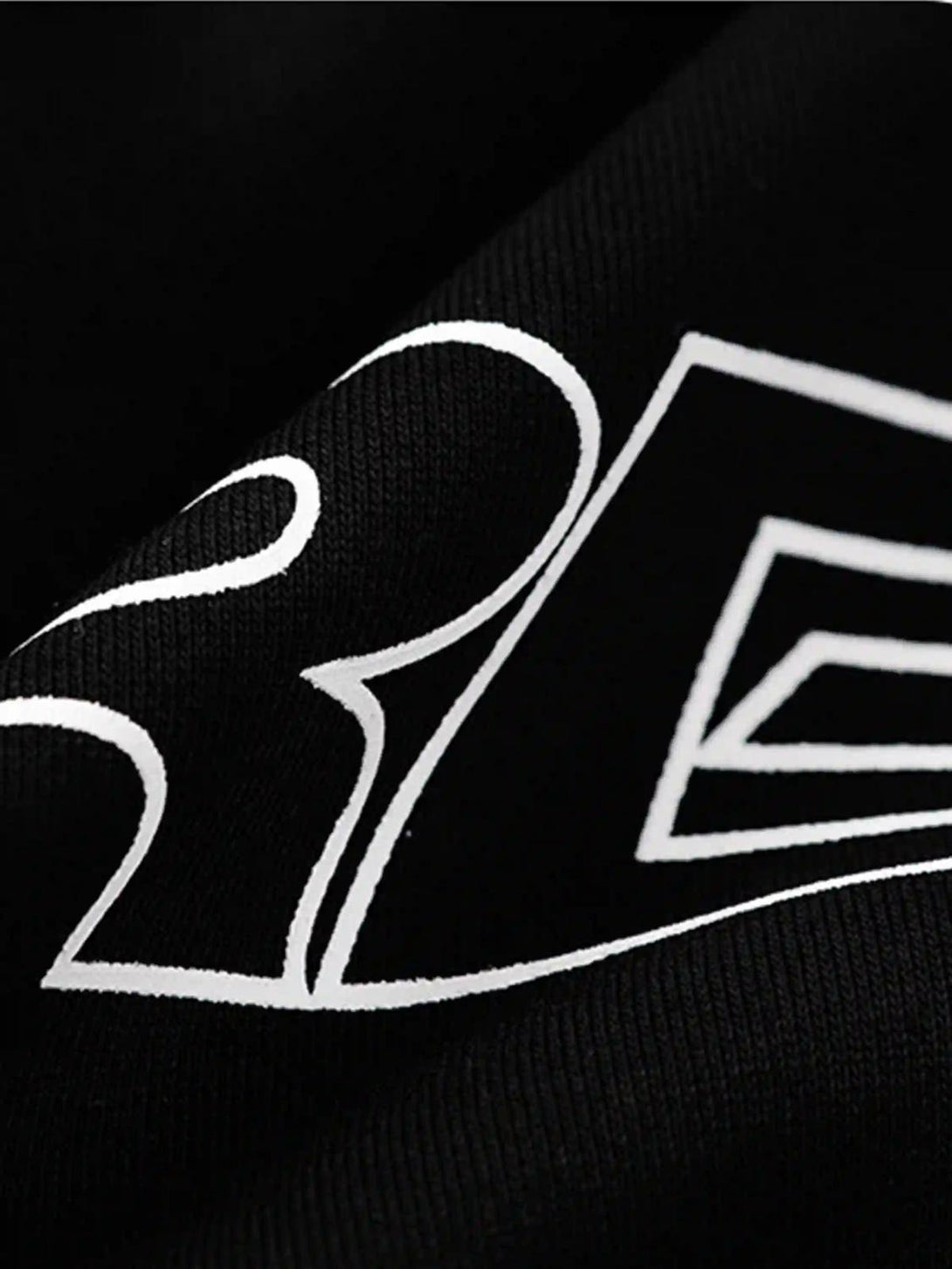 A detailed view of TALISHKO's black hoodie fabric, highlighting the letter print and line design.