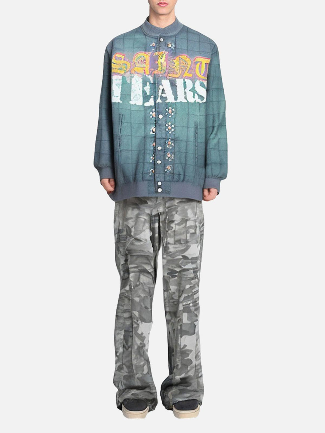 Model showcasing TALISHKO's quilted bomber jacket with bold lettering and camo pants.