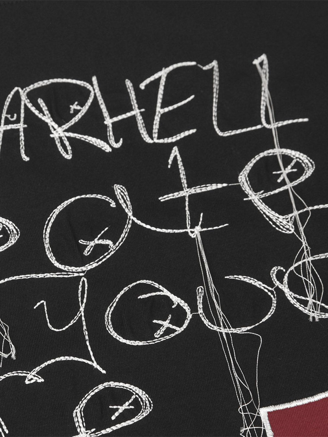 Detailed fabric and stitching on TALISHKO T-shirt, featuring white graphic lettering on black.