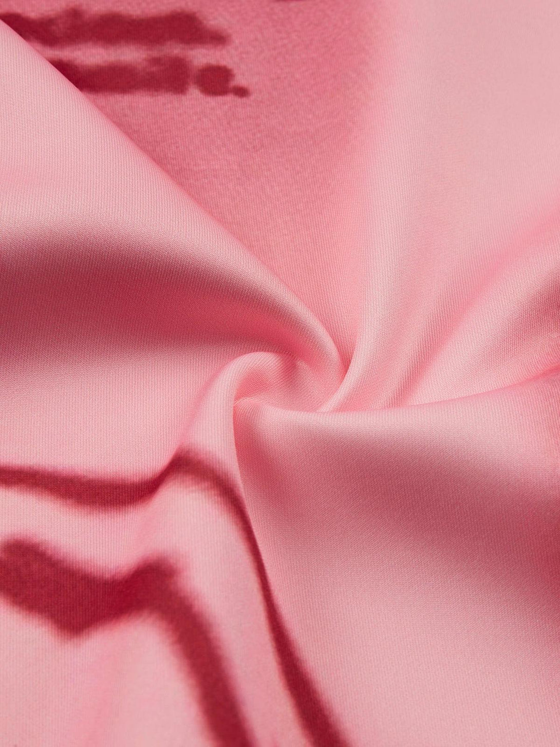 Zoomed-in texture of soft pink TALISHKO hoodie fabric, highlighting abstract red design.