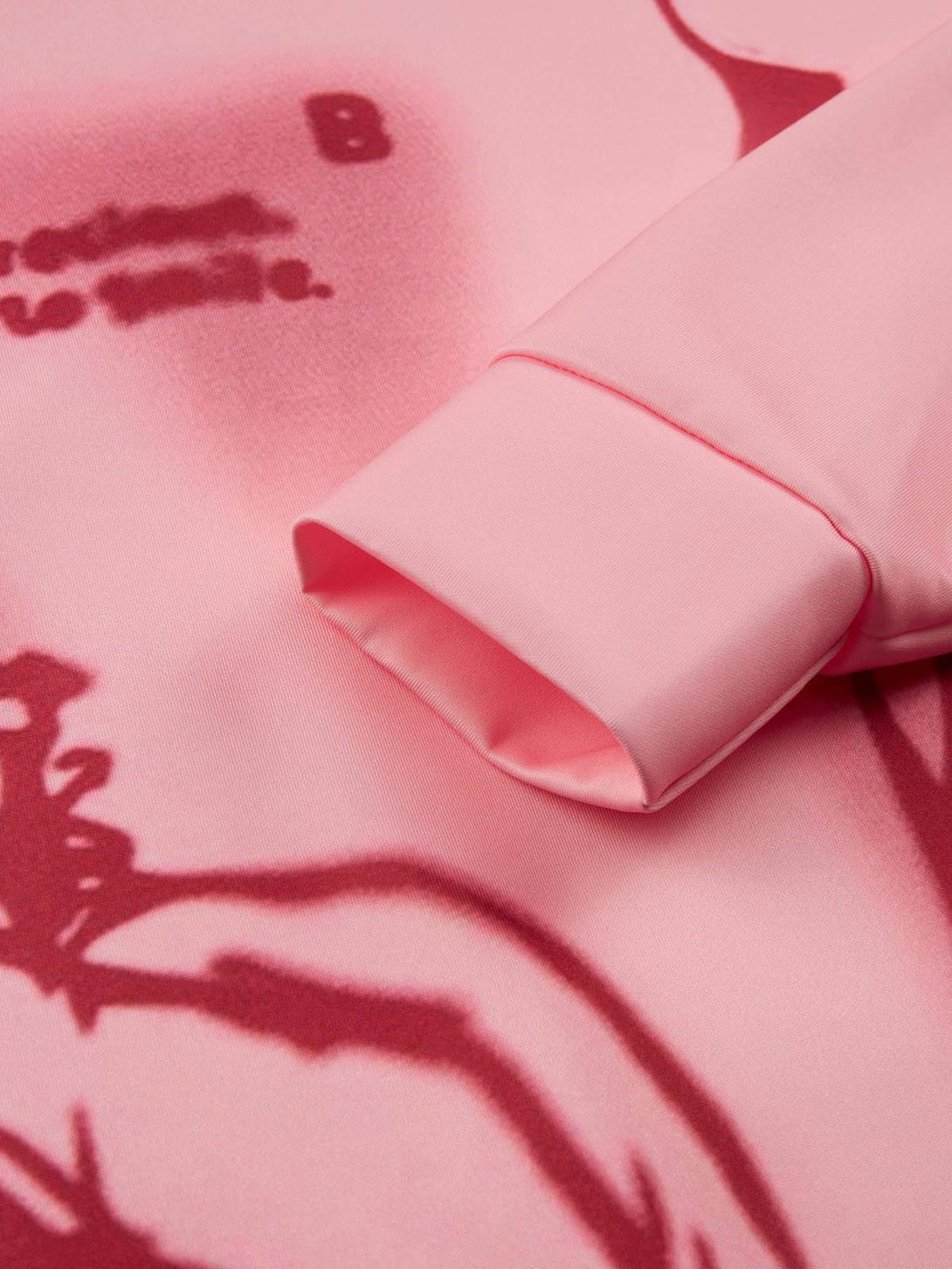 Intricate look at the pink TALISHKO hoodie sleeve, showcasing abstract red character design.