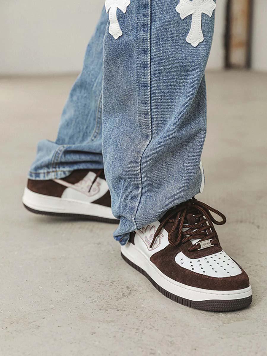 Model sporting TALISHKO skate sneakers in brown and white, paired with cross-detailed jeans.