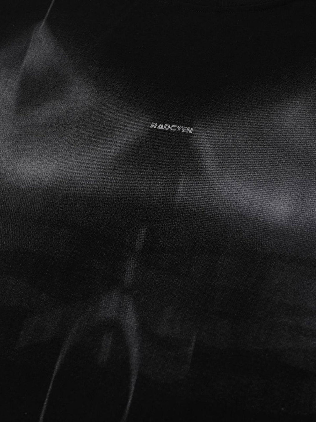 A detailed view of a black t-shirt by TALISHKO, focusing on its subtle print and texture.