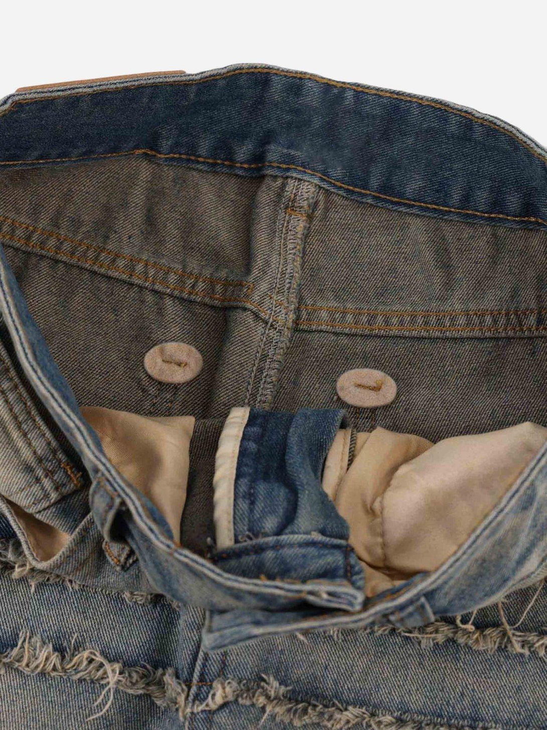 Intricate look at the inside button and frayed edge of TALISHKO jeans, showcasing rugged style.