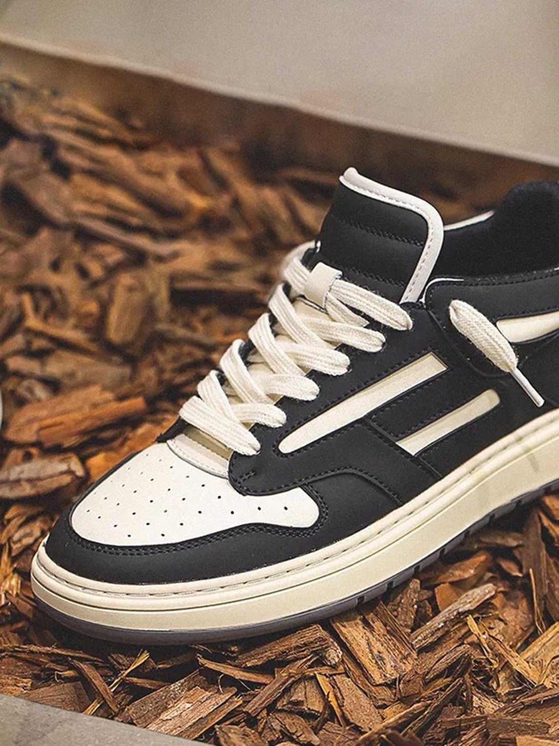 TALISHKO low-top sneakers in black and white, elegantly displayed on a wooden mulch background.