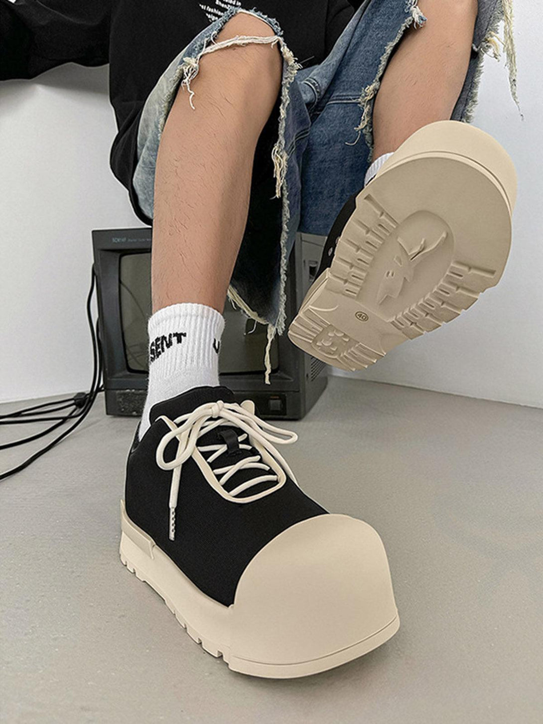 TALISHKO platform sneakers with chunky soles, paired with ripped jeans for a trendy look.