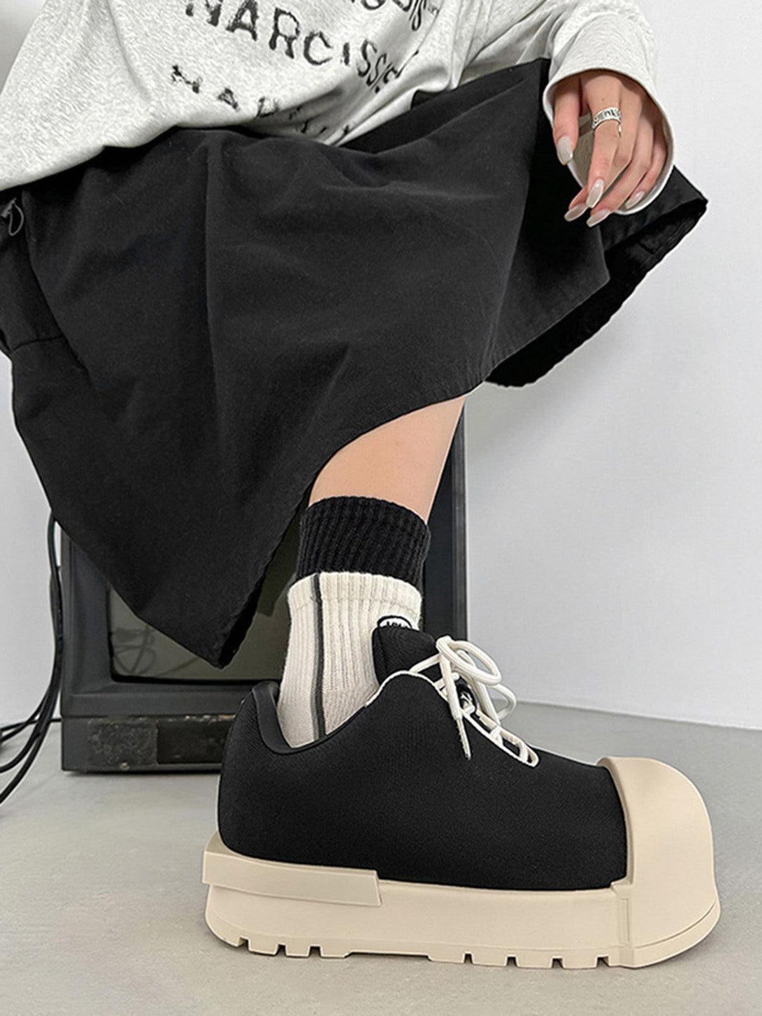 TALISHKO low top platform sneakers in black, styled with a skirt for a chic streetwear vibe.