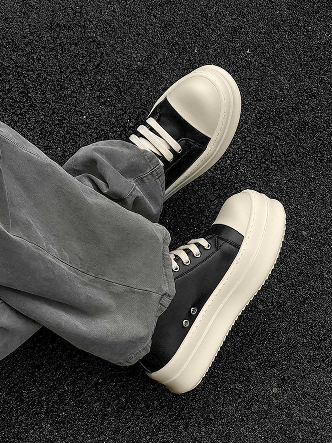 Low-top chunky sneakers by TALISHKO in black and cream, paired with casual gray pants.
