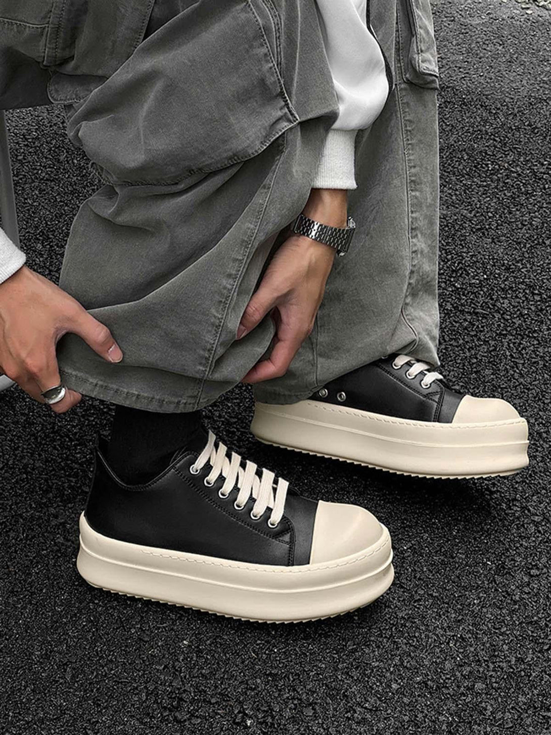 TALISHKO's low-top sneakers with chunky cream soles and black uppers, styled with gray pants.