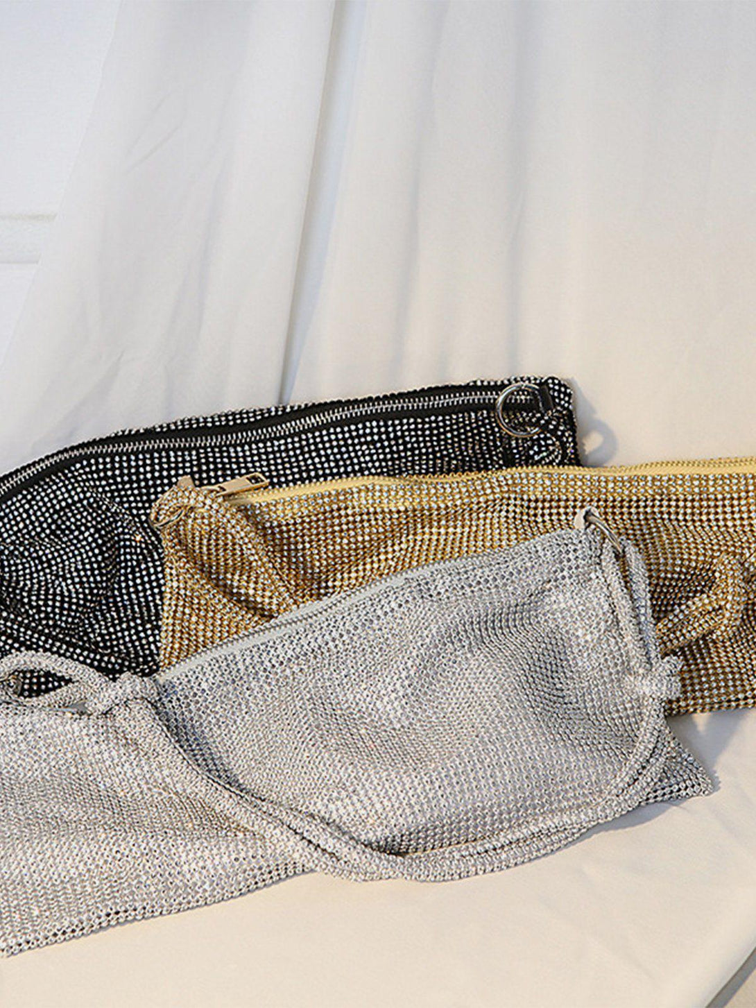 Three TALISHKO luxury diamond bags in silver, gold, and black, showcasing their shimmering textures.