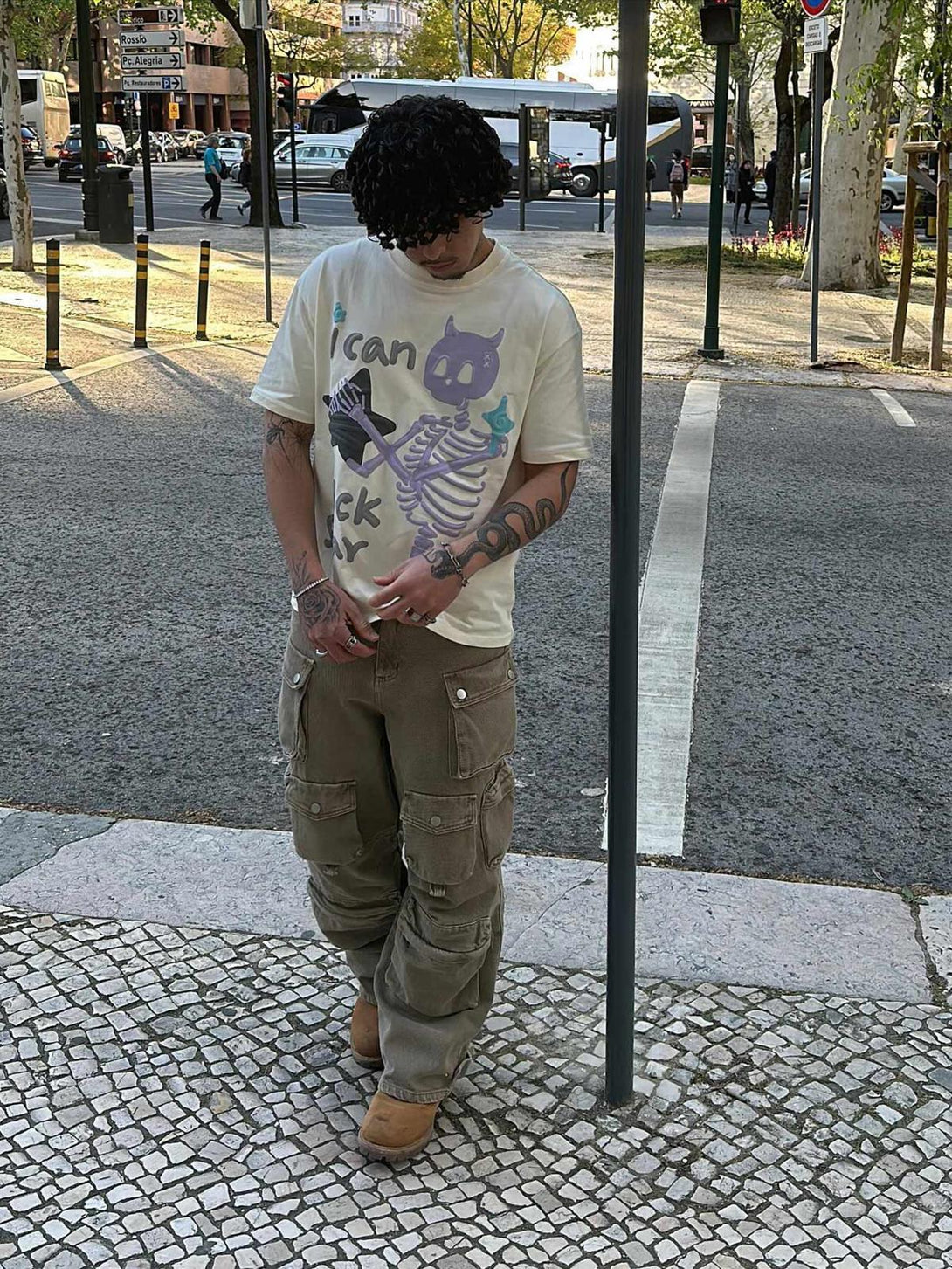 Model wears TALISHKO retro skeleton graphic T-shirt with cargo pants on a city street.