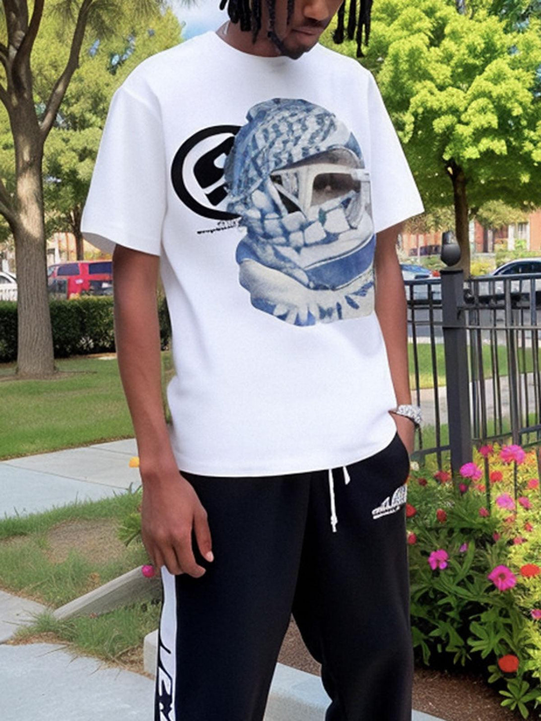 Model wearing TALISHKO's white T-shirt with a striking masked portrait graphic in a garden setting.