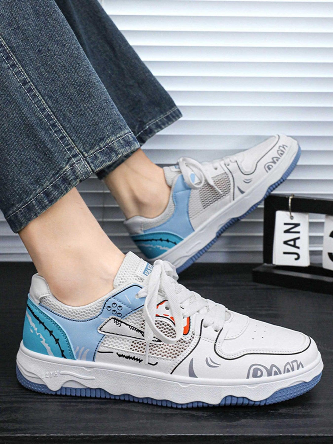 Mesh board shoes by TALISHKO feature vibrant graphics and blue details, paired with casual denim.